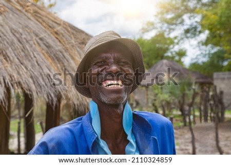 Happy elderly African man portrait, in front of his house in an African village