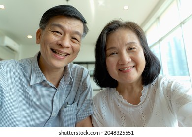 Happy Elderly Asian Couple Doing Facetime Video Calling With A Smartphone At Home Using The Zoom App, Online Meetings, Social Media, New Normal Concepts