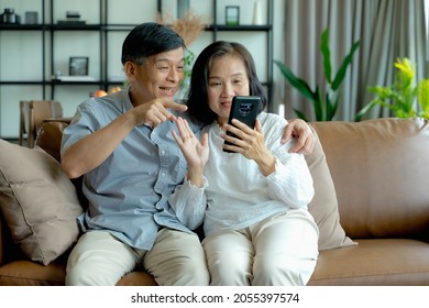 Happy Elderly Asian Couple Doing Facetime Video Calling With A Smartphone At Home Using The Zoom App, Online Meetings, Social Media, New Normal Concepts