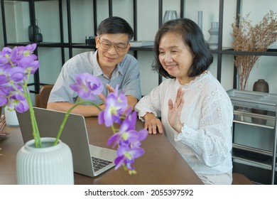 Happy Elderly Asian Couple Doing Facetime Video Calling With A Laptop At Home Using The Zoom App, Online Meetings, Social Media, New Normal Concepts