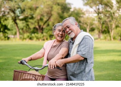 Happy Elderly Asian Couple Walking Talking Together With Bicycles In The Park. Holiday Activities For Retired Couples.