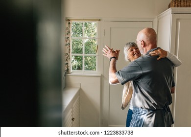 Happy Elderly Couple Dancing Together Holding Each Other. Romantic Senior Couple Having Fun Doing Ballroom Dancing At Home.