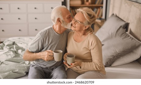 Happy elderly couple enjoying coffee or tea in bed  - Powered by Shutterstock