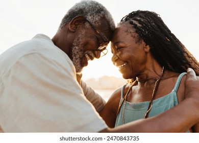 Happy elderly couple enjoying a moment of love on the beach. Both have joyful expressions and the woman has beautiful braids. - Powered by Shutterstock