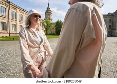 Happy Elderly Couple Holding Hands While Walking Outdoors