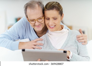 Happy Elderly Couple Looking At A Tablet As They Are Surfing The Internet