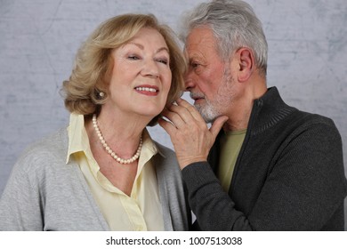 Happy Elderly Couple In Love. Old Man Whispering Secret To His Wife