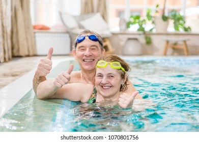 happy elderly couple in the pool showing thumbs up - Shutterstock ID 1070801756