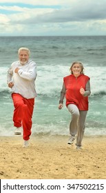 Happy Elderly Couple Running  On A Beach