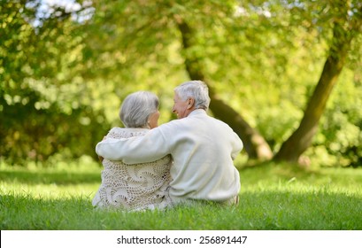 Happy Elderly Couple Sitting In Autumn Park