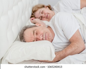 Happy Elderly Couple Sleeping Together On The Bed