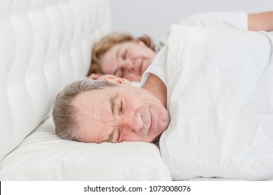 Happy Elderly Couple Sleeping Together On The Bed