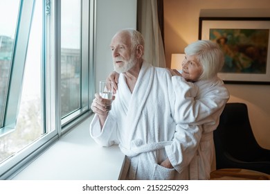 A happy elderly couple standing near the window in the hotel - Powered by Shutterstock