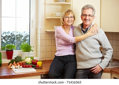 Happy Elderly Couple Standing Smiling In A New Kitchen