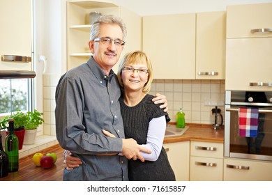 Happy Elderly Couple Standing Smiling In A New Kitchen