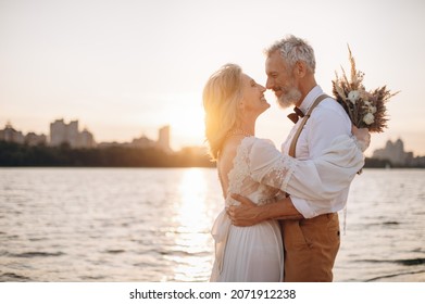 Happy elderly couple in wedding dress looking at each other in sun.