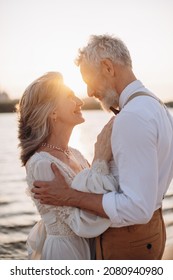 Happy Elderly Couple In Wedding Dress Looking At Each Other In Sun.