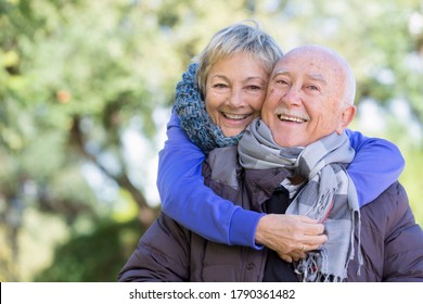 happy elderly couple with winter clothes lovingly embraces each other at the park - Powered by Shutterstock