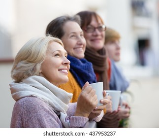 Happy Elderly Female Friends Drinking Coffee At Patio. Focus On Blonde