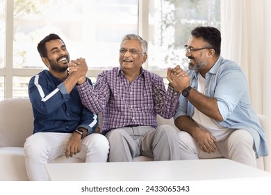 Happy elderly Indian grandpa shaking hands in friendship gesture with mature son and young adult grandson, getting support, enjoying strong family relations, generations bonding - Powered by Shutterstock