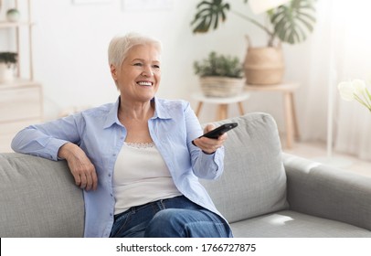 Happy Elderly Lady Watching Tv At Home, Sitting On Couch With Remote Controller, Switching Channels, Copy Space