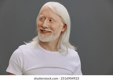 Happy elderly man with long white hair and beard smiling against a neutral gray background, showcasing a joyful expression and a casual white t shirt - Powered by Shutterstock