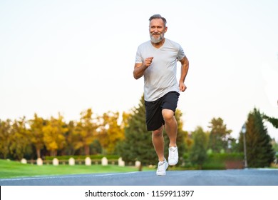 The Happy Elderly Man Running On The Road