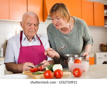 Happy Elderly Man And Woman Making Dinner Together In Kitchen