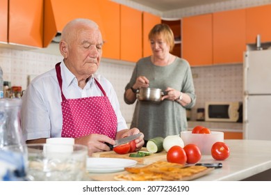 Happy Elderly Man And Woman Making Dinner Together In Kitchen