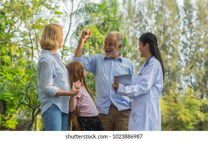 Happy Elderly Patient Man Show Strong With Doctor Woman And His Family In The Park