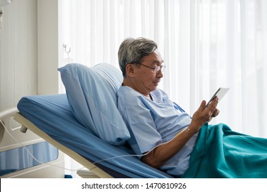 Happy Elderly Patient Sitting On Bed And Making Video Call With Tablet At Hospital