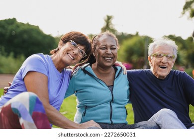 Happy elderly people having fun hugging each other outdoor after yoga lesson - Powered by Shutterstock