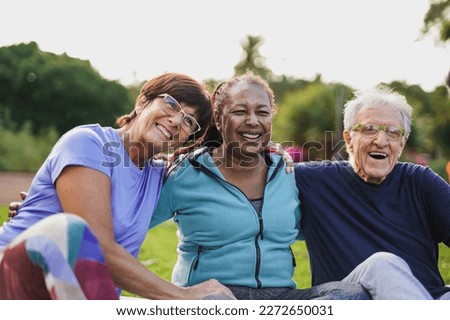 Happy elderly people having fun hugging each other outdoor after yoga lesson