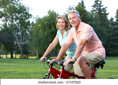 Happy Elderly Senior Couple Biking In Park