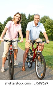 Happy Elderly Senior Couple Cycling In Park