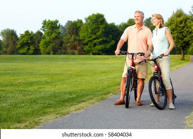 Happy Elderly Senior Couple Cycling In Park