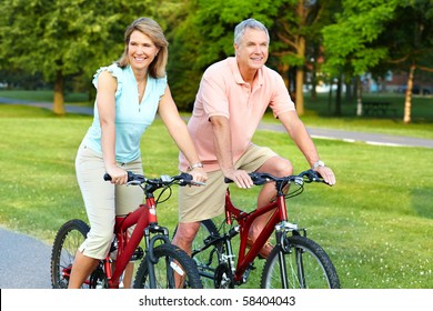 Happy Elderly Senior Couple Cycling In Park