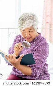 Happy Elderly Senior Woman Female Lady Enjoy Reading Book Using Magnifying Glass