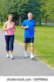 Happy Elderly Seniors Couple Jogging In Park