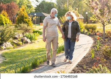 Happy Elderly Seniors Couple Wearing Medical Mask To Protect From Coronavirus In Summer Park