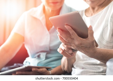 Happy elderly twin senior people society lifestyle concept. Ageing Asia women using tablet share social media together in wellbeing county home.