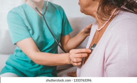 Happy Elderly Woman Assisted By Geriatric Doctor, Examination In The Nursing Home.  Health Visitor And A Senior Woman During Home Visit. Medicine, Age, Support, Health Care And People Concept