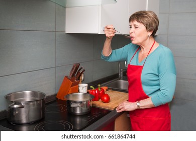 Happy Elderly Woman Cooking  In Kitchen At Home