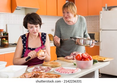 Happy Elderly Woman And Her Adult Daughter Making Dinner Together In Kitchen