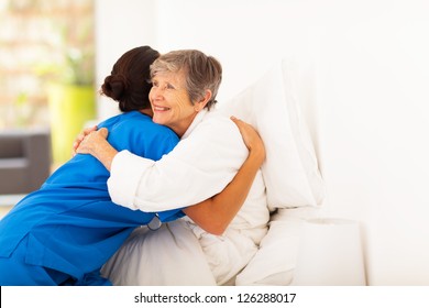 Happy Elderly Woman Hugging Caregiver On Bed