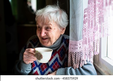Happy elderly woman portrait sitting at the table and drink tea.