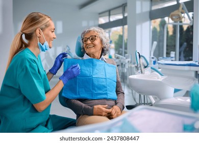 Happy elderly woman talking to her orthodontist during appointment at dentist's office. - Powered by Shutterstock