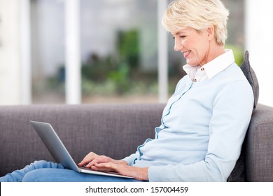 Happy Elderly Woman Using Laptop Computer At Home