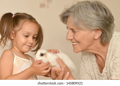 happy elderly woman and a young girl with a small rabbit - Powered by Shutterstock