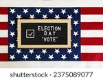 Happy Election Day letter board with Vote check mark against American flag background. Don